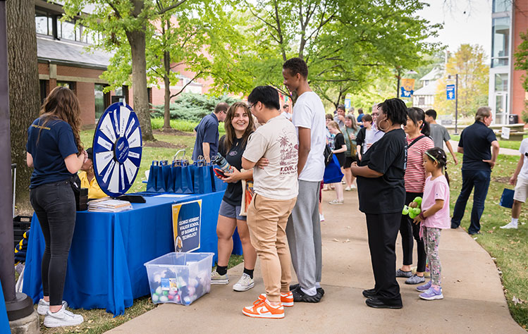 Attendees line up to spin a wheel at a booth.