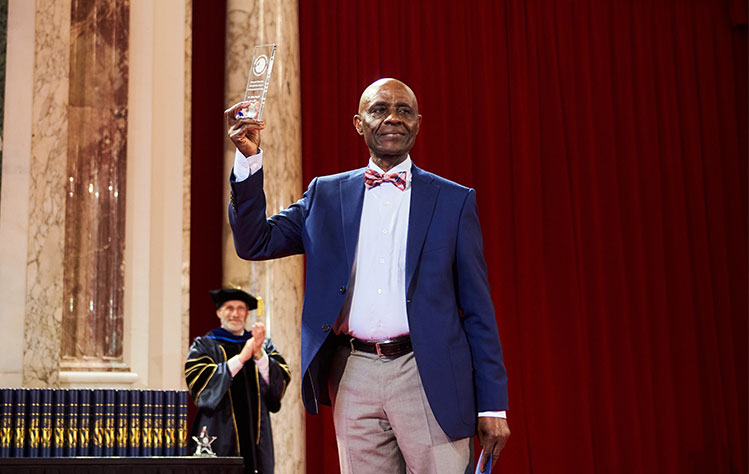 Onyeji holds up his award at Webster Vienna's Commencement ceremony.