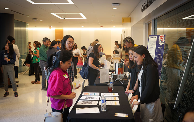 A pair of attendees stand at a resource fair table in Webster's Interdisciplinary Science Building.