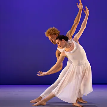 Senior Faith Carson (front) and sophomore Keenon Hamburg (back) perform a dance against a purple background.