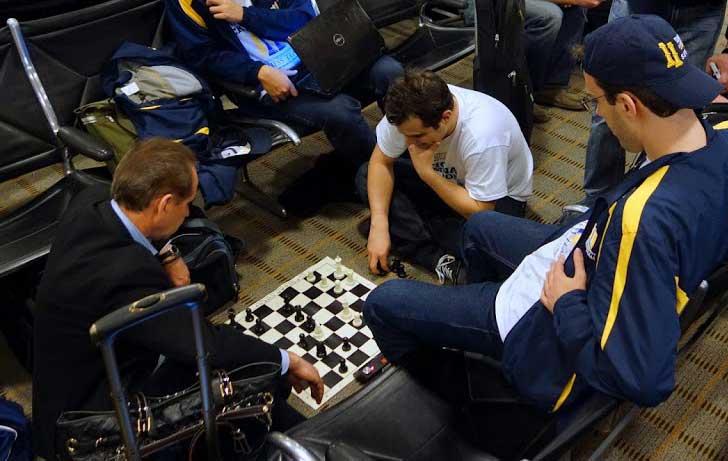 Julian Schuster plays chess while waiting for a flight at an airport