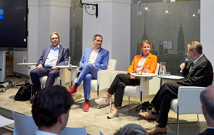 Panelists sitting in front of the crowd at the event.