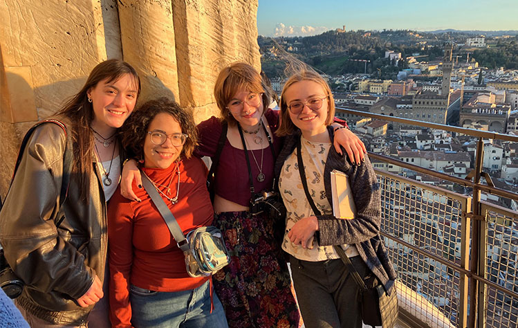 Four Webster students smile for a photo with the landscape of Florence behind them.