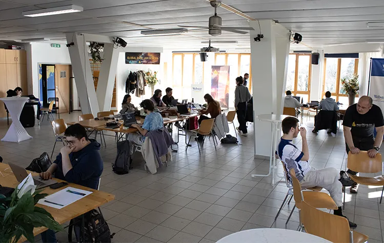 Teams around the room concentrate at separate tables in a bright and airy room during the 48 hour Global Game Jam event at Webster Geneva.