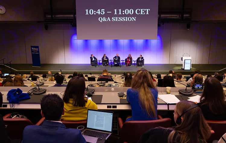 Panelists sit onstage in a large lecture hall full of attendees.