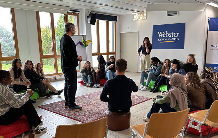 Webster students sit in a circle in a classroom in Webster Geneva for a workshop.