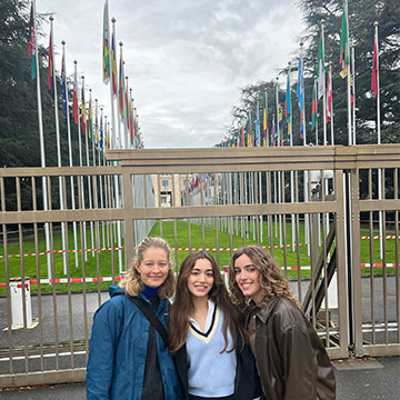 Three Webster students smile in front of the Alley of Flags.