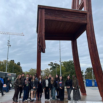 Webster students stand under artwork in the form of an oversized chair.