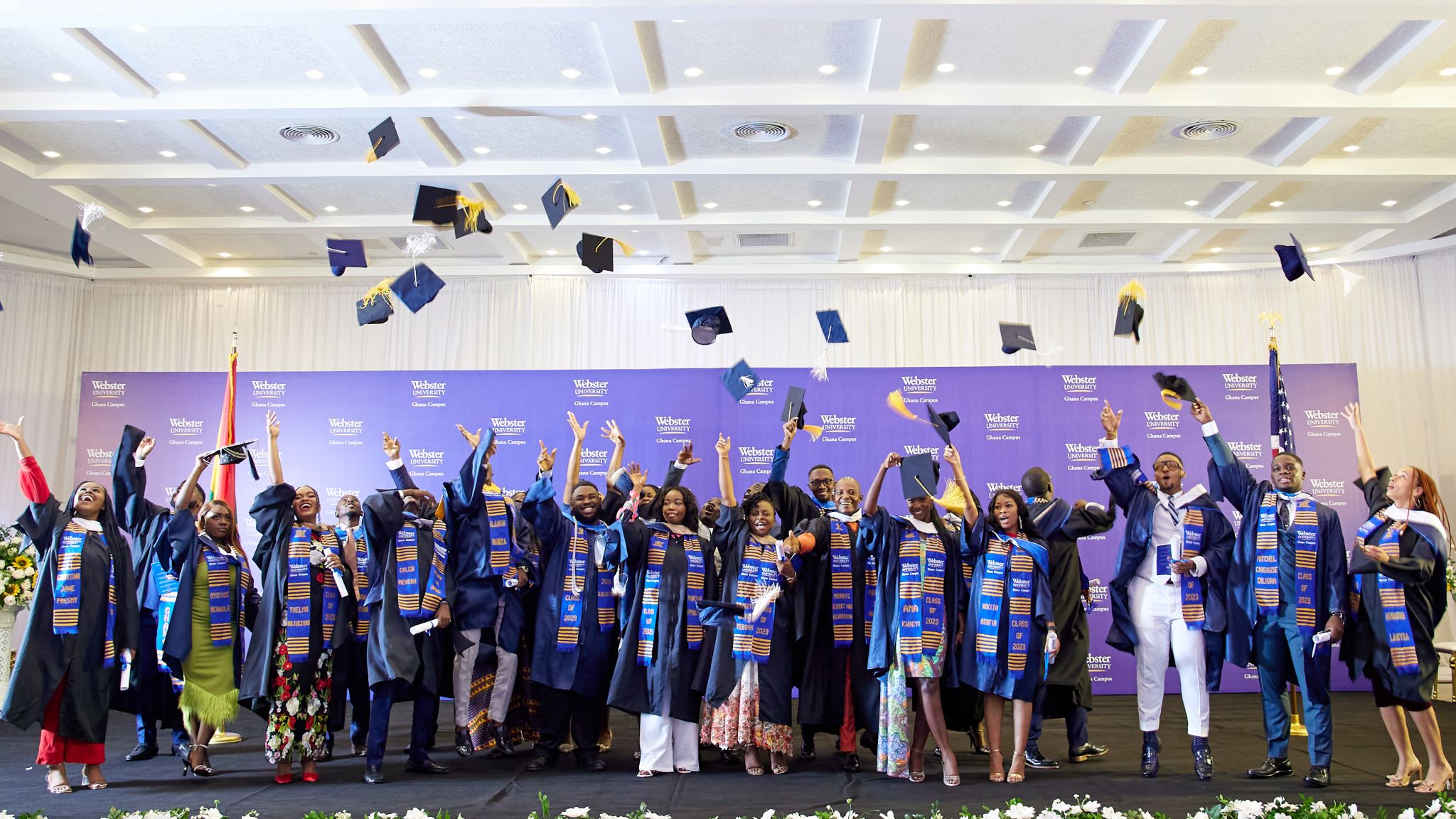 Graduates at Webster Ghana toss their caps in the air.