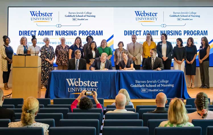 Webster University President Tim Keane and Barnes-Jewish College Goldfarb School of Nursing President Angela Clark sign the parternship agreement during a ceremony on Webster's campus.
