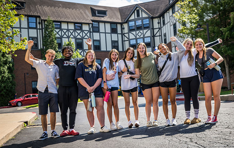 Webster University students standing outside of a dorm on move-in day, full of energy for the year ahead.