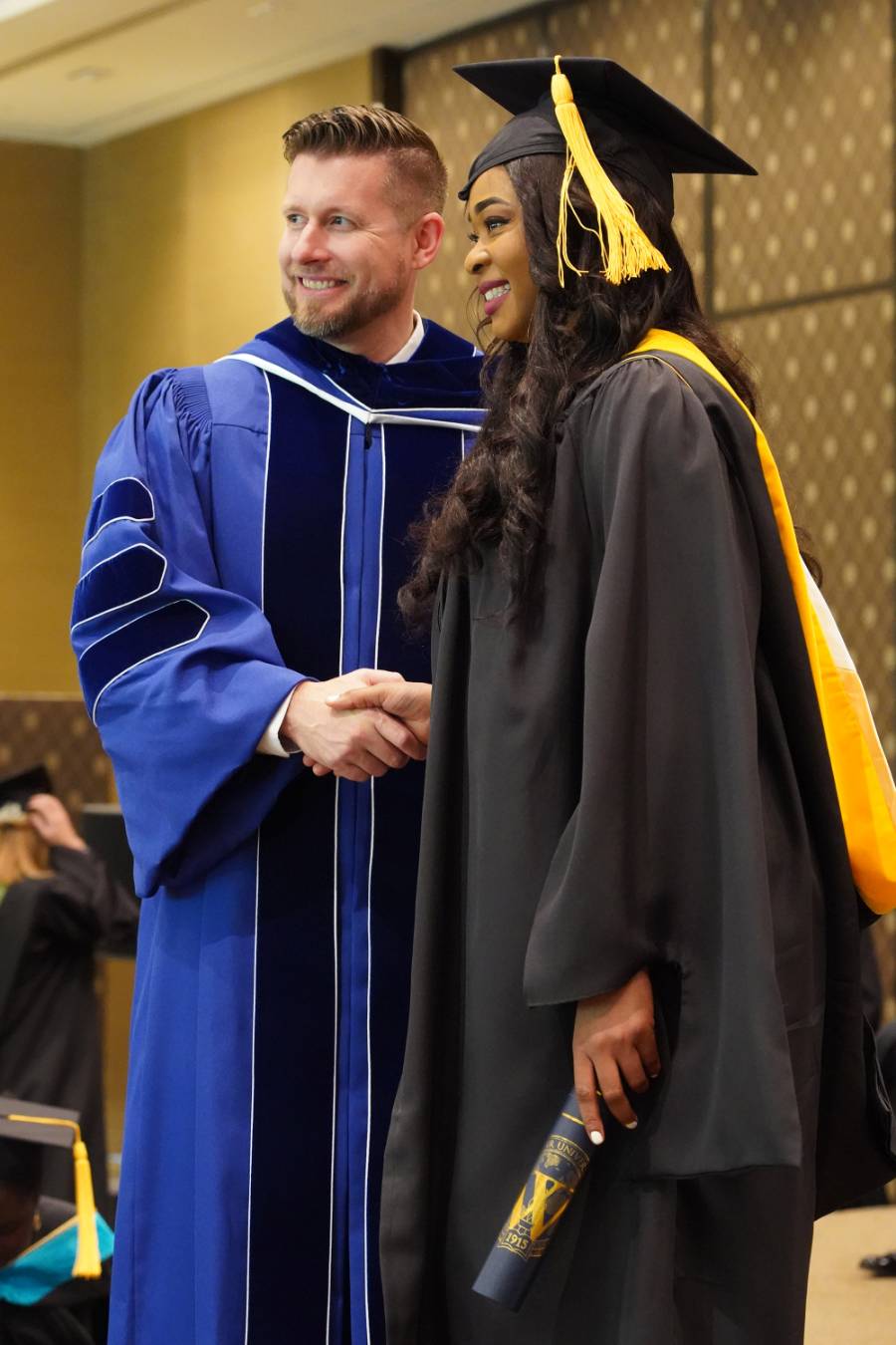 Guffey congratulates a Webster graduate who travelled from Ghana to walk at Geneva's commencement ceremony.