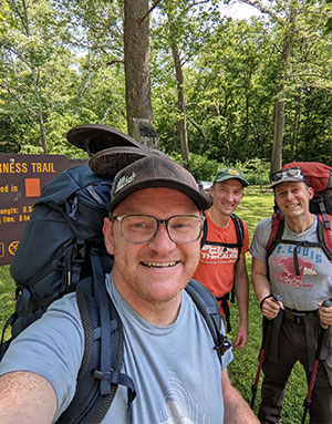 From left to right: Rich, Kennedy and McKenzie smile by a trail sign during a recent hike.