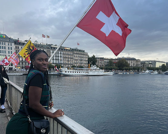 Kristen McLauchlin pictured under a Swiss flag by the water on a dock.