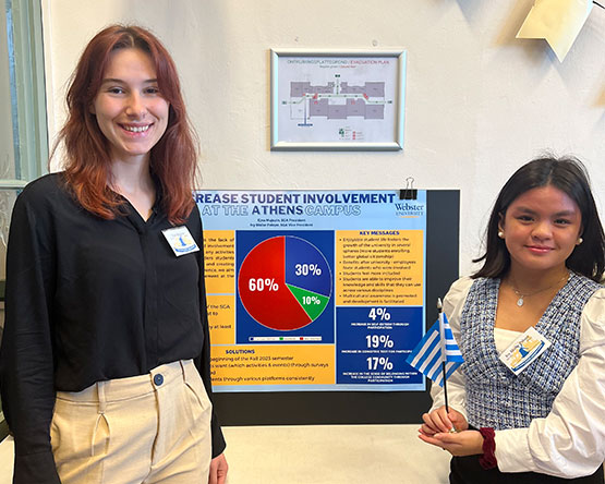 Two students from Webster Athens stand in front of their action plan display board which focuses on increasing student involvement at Webster Athens.