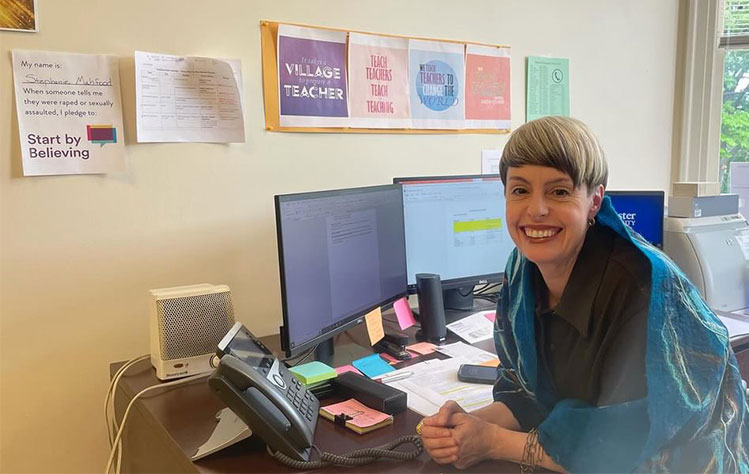 Stephanie Mahfood sits at her desk with her Start By Believing Pledge on the wall next to her.