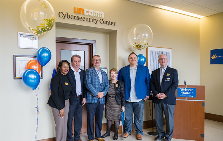 In front of the newly opened UNCOMN Cybersecurity Center: Dean of the Walker School of Business and Technology Simone Cummings, Webster University President Julian Schuster, UNCOMN CEO Jason Carter, Webster University Chancellor Beth Stroble, UNCOMN Chief Information Systems Officer Cory Phipps, and Webster University Information Technology and Cybersecurity Program Director Jim Curtis.