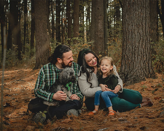 McInnis and her family are seated in the woods together on a fall day.