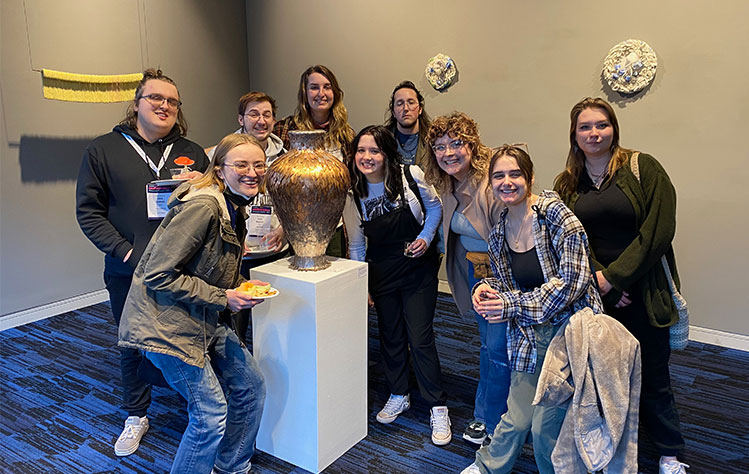 Webster Clay Club students pose for a photo with art at the NCECA Conference.