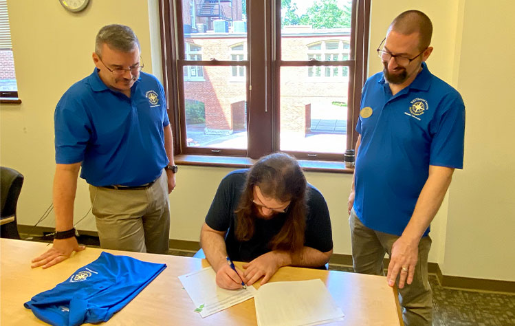 Scoggin signs paperwork to officially make him the first WESTbound Success Scholarship Recipient.