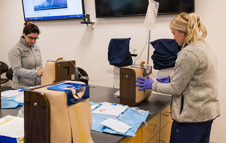 Two students practice with needles in a Doctor of Nurse Anesthesia course.