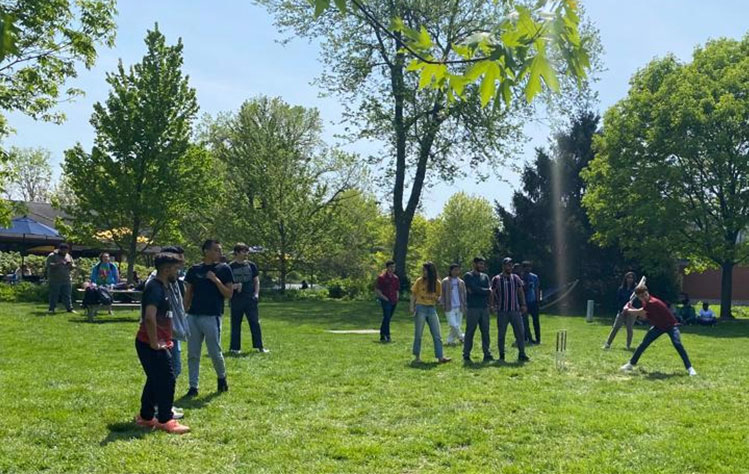 A group of Webster students play cricket.