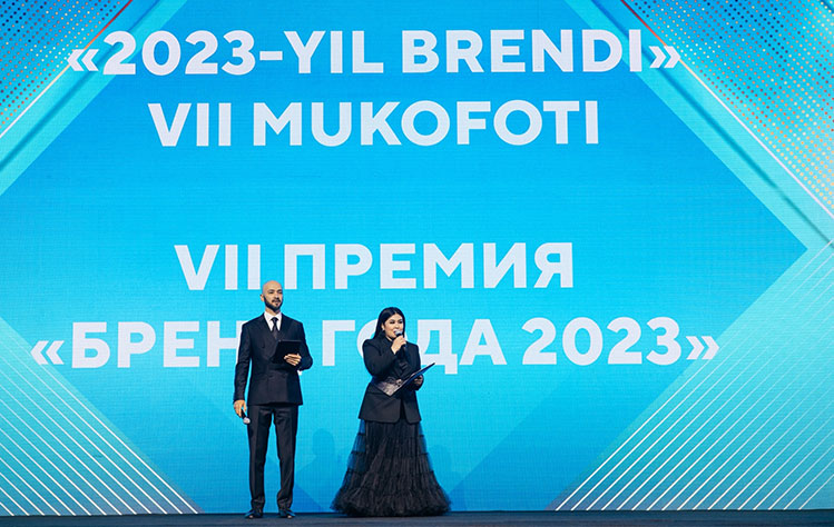 Two people stand in front of a digital screen at the award ceremony.