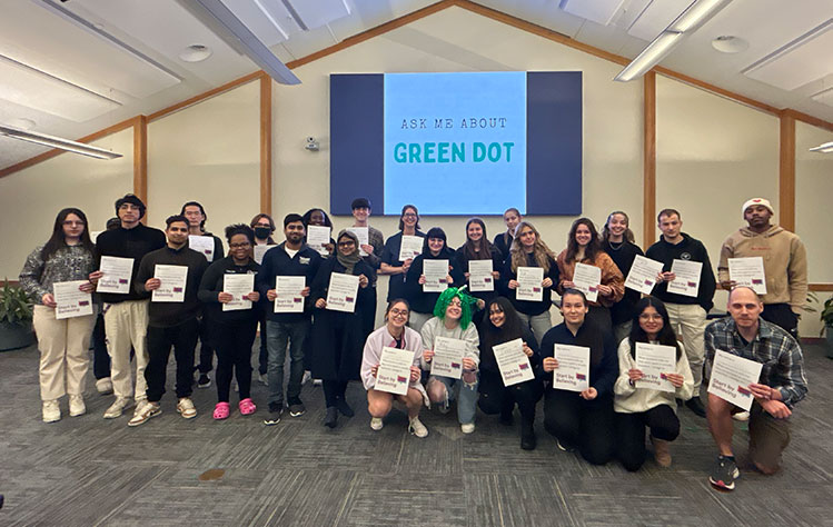 A group in the University Center holds their Start by Believing Pledges after completing Green Dot Training.