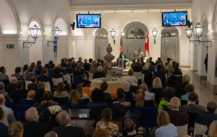 Victoria Reggie Kennedy and Doris Kearns Goodwin sit onstage in a crowded room of attendees in the Palais Wenkheim.