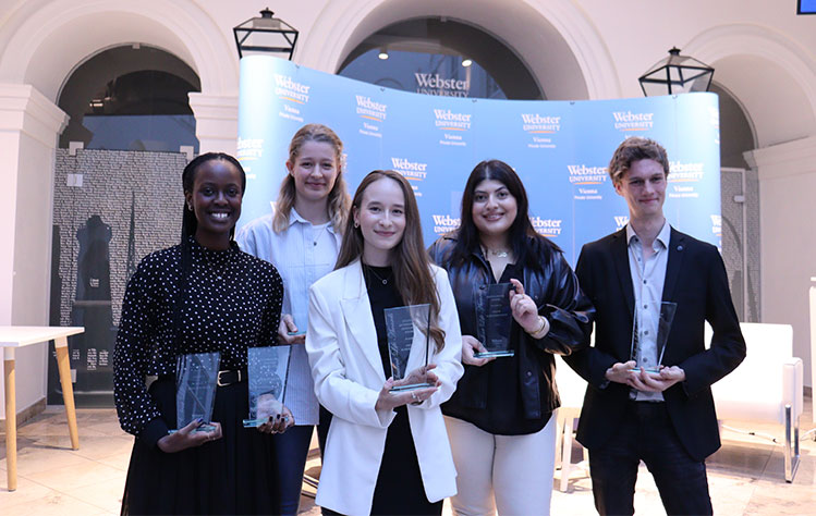 Five student awardees hold plaques while smiling.
