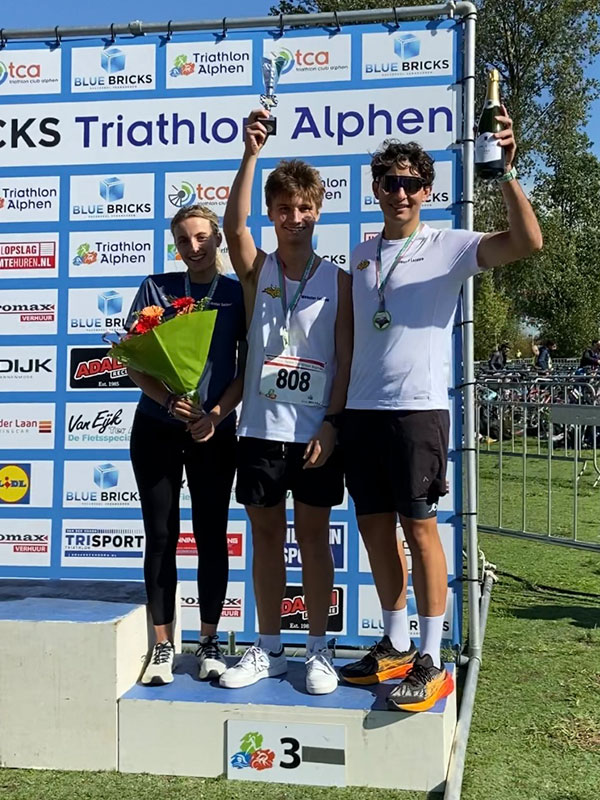 Udo, Gavca, and Decrock stand on the third place podium after finishing the triathlon. 